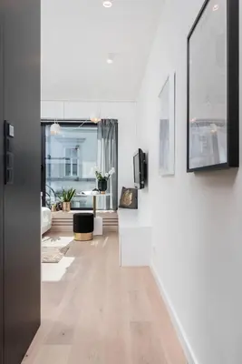 a living room with white walls and a hallway with wooden floors at White Room Piłsudskiego 1 in Kraków
