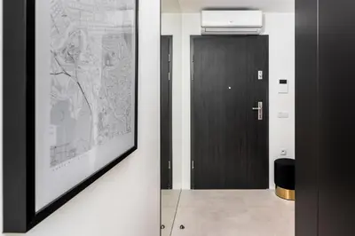 a hallway with a black door and a picture on the wall at White Room Piłsudskiego 1 in Kraków