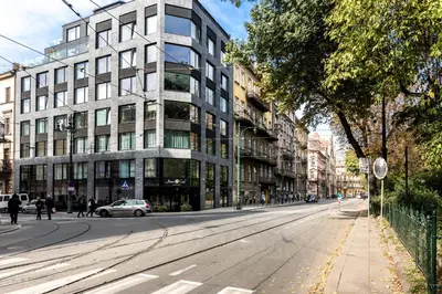 an empty street in a city with a building at White Room Piłsudskiego 1 in Kraków