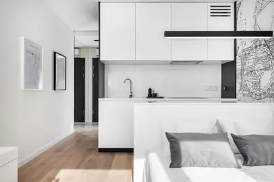 a kitchen with white cabinets and a couch in a room at White Room Piłsudskiego 1 in Kraków