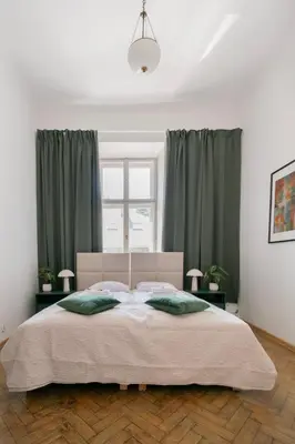 a bedroom with a large bed with green curtains at Apartments Studencka Street, Next to Planty Park in Kraków