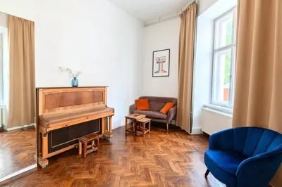 a living room with a piano and a blue chair at Apartments Studencka Street, Next to Planty Park in Kraków