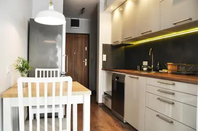 a kitchen with white cabinets and a wooden table at Dworska 1A - studio by Homeprime in Kraków