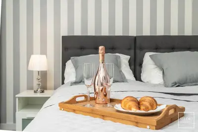 a tray with bread and wine glasses on a bed at Exclusive Vermelo Apartment in Kraków