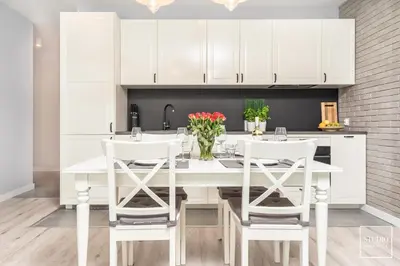 a kitchen with white cabinets and a white table and chairs at Exclusive Vermelo Apartment in Kraków