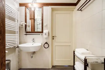 a white bathroom with a sink and a mirror at Elegant Apartments in Kraków