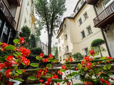 a garden with red flowers in front of two buildings at Elegant Apartments in Kraków