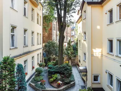 an apartment courtyard with a tree and plants at Elegant Apartments in Kraków