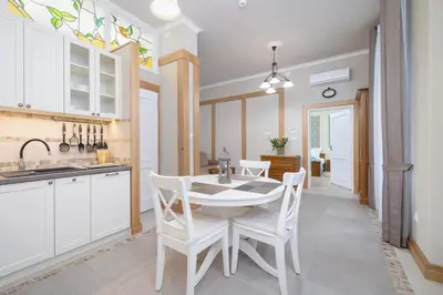 a kitchen with white cabinets and a table and chairs at Elegant Apartments in Kraków