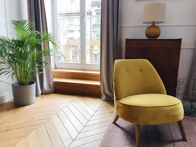 a yellow chair in a living room with a window at TCF Home - Apartment with Free Garage in Kraków