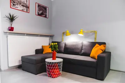 a living room with a black couch and yellow pillows at ULMA apartment in Wieliczka