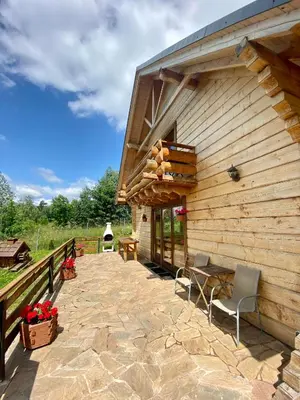 a patio of a wooden building with a table and chairs at Górska Przystań in Wola Piskulina