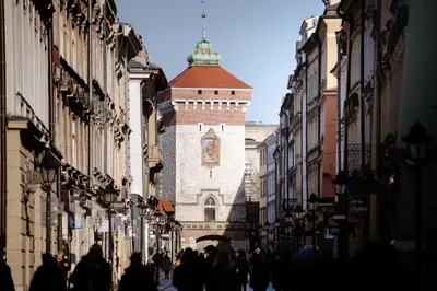 a group of people walking down a street with a clock tower at Hotel Unicus Krakow Old Town - Destigo Hotels in Kraków