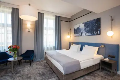 a hotel room with a bed and a table and chairs at Hotel Unicus Krakow Old Town - Destigo Hotels in Kraków