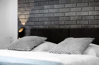 two pillows on a bed with a brick wall at Native Apartments Lubelska 10 in Kraków