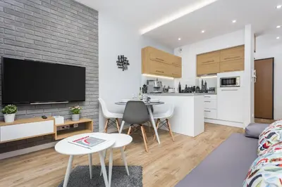 a kitchen and living room with a table and a tv at City of the Kings-Silver Apartment No 2- Lubelska 10 in Kraków