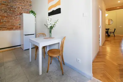 a white table with two chairs and a vase with flowers at Vintage Apartment Gertrudy street in Kraków