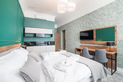 a bedroom with two beds and a desk and a television at Vinfort Aparthotel in Kraków