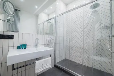 a white bathroom with a sink and a shower at Vinfort Aparthotel in Kraków