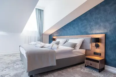 a bedroom with a large bed with a blue wall at Vinfort Aparthotel in Kraków