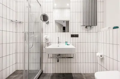 a white tiled bathroom with a sink and a shower at Vinfort Aparthotel in Kraków