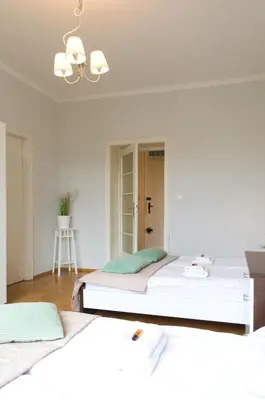 a white bedroom with two beds and a chandelier at Unique apartments Krasinskiego street in Kraków