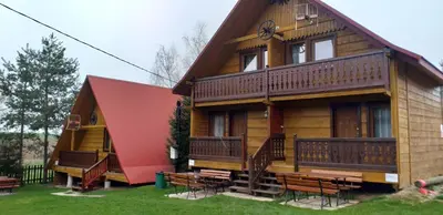 a large wooden house with benches in front of it at Zajazd na Podzamczu in Pieskowa Skała