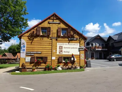 a large wooden building with a sign in front of it at Zajazd na Podzamczu in Pieskowa Skała