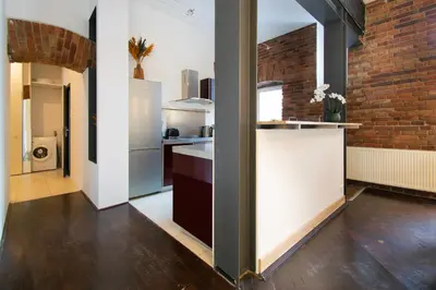 a kitchen with a white counter and a brick wall at Apartments Wróblewskiego Street in Kraków
