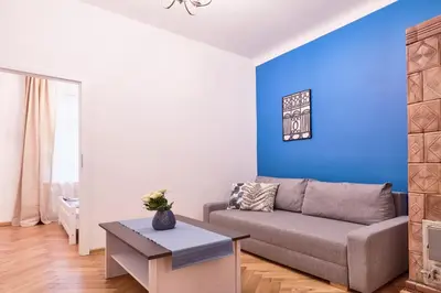 a living room with a couch and a blue wall at Spacious Apartments Zyblikiewicza Street in Kraków