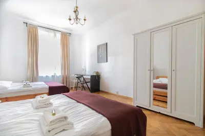 a white bedroom with two beds and a window at Spacious Apartments Zyblikiewicza Street in Kraków