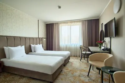 a hotel room with two beds and a desk at Metropolo by Golden Tulip Krakow in Kraków