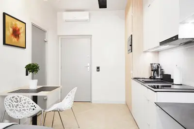 a white kitchen with a table and chairs at Compact Studios Słowackiego Avenue in Kraków