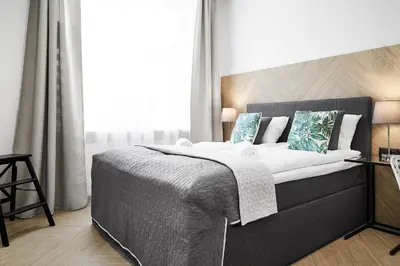 a bedroom with a large bed with white and blue pillows at Compact Studios Słowackiego Avenue in Kraków
