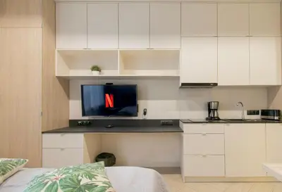 a kitchen with white cabinets and a tv on a counter at Compact Studios Słowackiego Avenue in Kraków