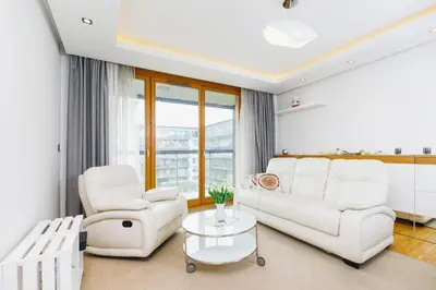 a living room with a white couch and two chairs and a table at Apartments Kraków Masarska Free Parking by Noclegi Renters in Kraków