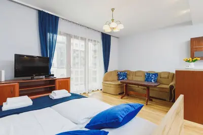 a bedroom with a bed and a tv and a couch at Apartments Kraków Wiślane Tarasy by Noclegi Renters in Kraków