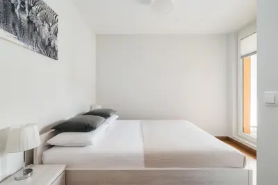 a white bedroom with a large bed and a window at Native Apartments Masarska 8 in Kraków