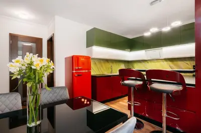 a kitchen with red and green cabinets and a vase of flowers at Native Apartments Masarska 8 in Kraków