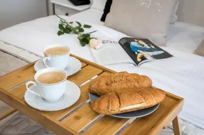two cups of coffee and two cookies on a tray on a bed at Angel Apartament in Kraków