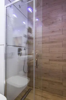 a shower with a glass door in a bathroom at Angel Apartament in Kraków