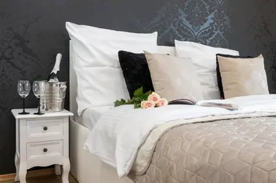 a bed with white pillows and a table with a night stand at Angel Apartament in Kraków