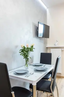 a dining room table with chairs and a vase of flowers at Angel Apartament in Kraków