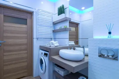a bathroom with a sink and a washing machine at Angel Apartament in Kraków