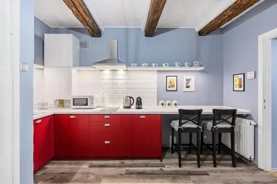 a kitchen with red cabinets and black stools at The Angels Apartments Krakow Old Town in Kraków