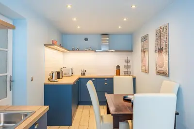a kitchen with blue cabinets and a wooden table at The Angels Apartments Krakow Old Town in Kraków