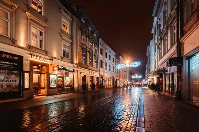 an empty city street at night with buildings at The Angels Apartments Krakow Old Town in Kraków