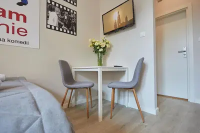 a bedroom with a table with two chairs and a vase of flowers at FLORIANSKA 32 by PI Apartments in Kraków
