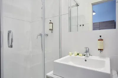 a white bathroom with a sink and a shower at FLORIANSKA 32 by PI Apartments in Kraków