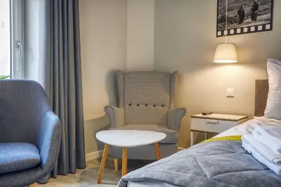 a bedroom with a chair and a table next to a bed at FLORIANSKA 32 by PI Apartments in Kraków